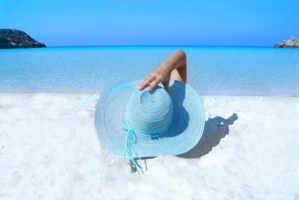 海辺でブルーの帽子をかぶる女性