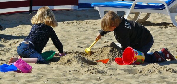 ビーチの砂で砂遊びをする2人の子ども